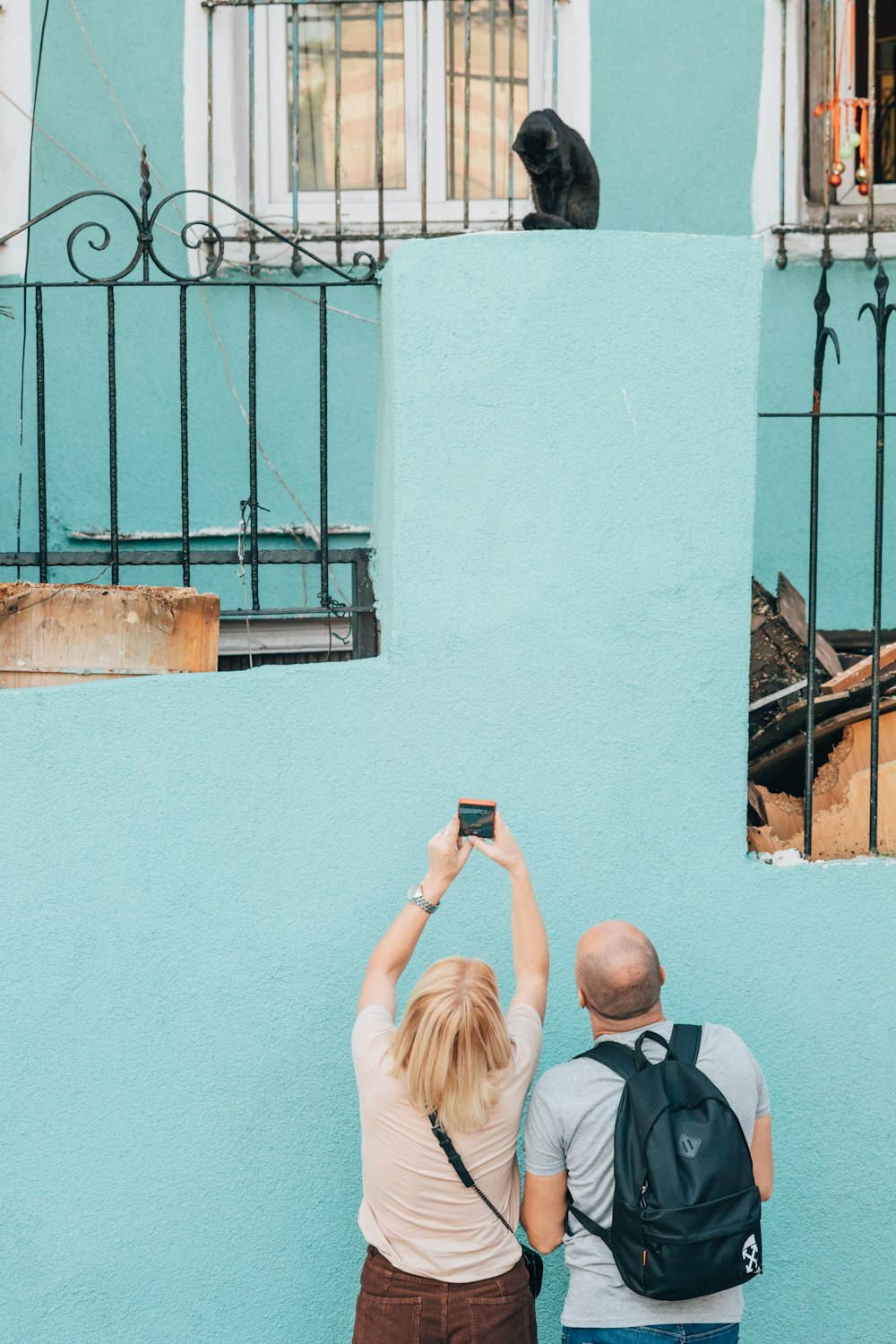 a man and a woman taking a picture of a cat