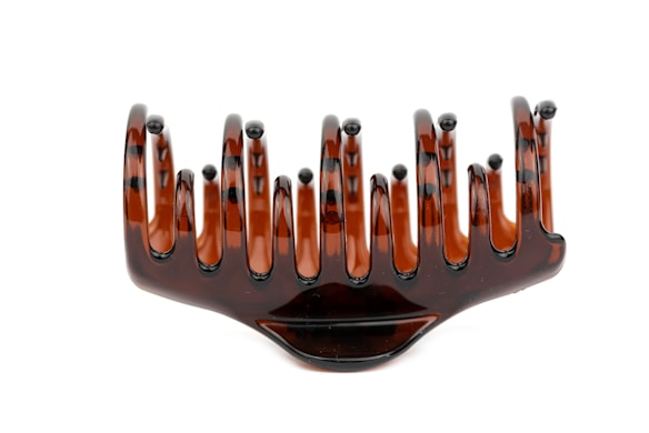 A large, brown, tortoiseshell-patterned hair claw clip with wide, curved prongs designed to hold hair securely.