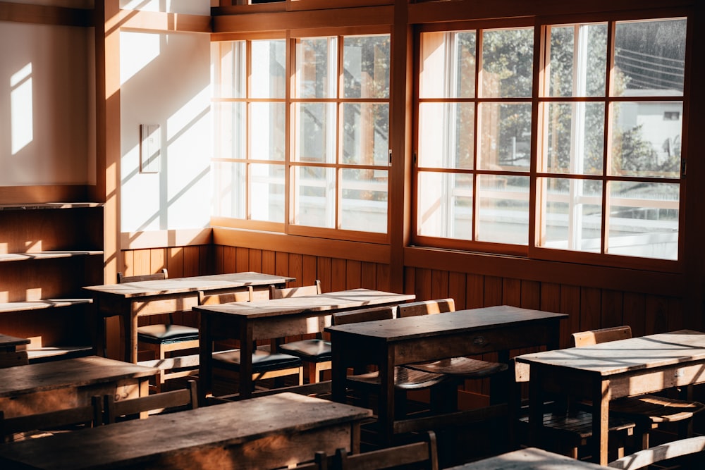 an empty classroom with wooden desks and windows