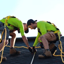 a couple of men working on a roof