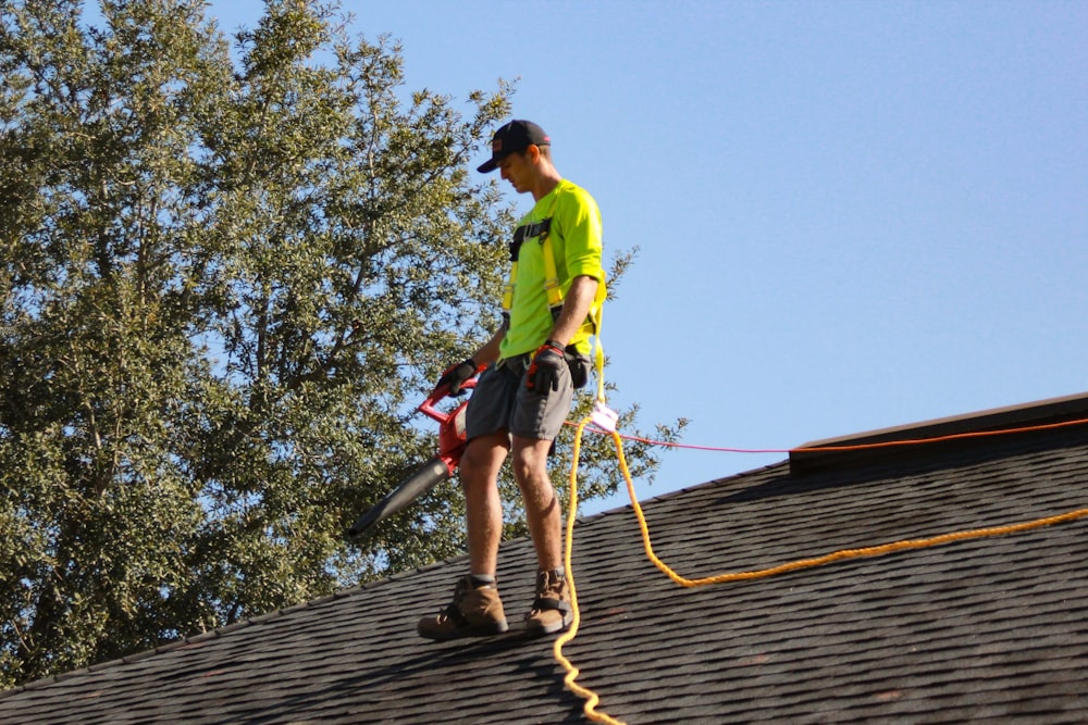 a man in a yellow shirt with a chainsaw on a roof
