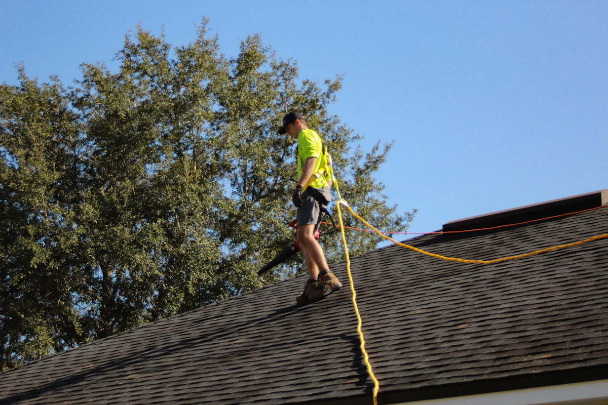 Roofer carefully installing shingles near a roof edge