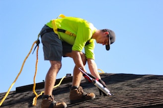 a man in a yellow shirt is working on a roof