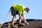 a man in a yellow shirt is working on a roof