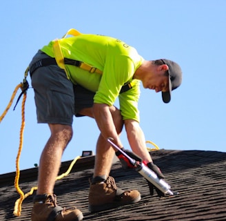 a man in a yellow shirt is working on a roof