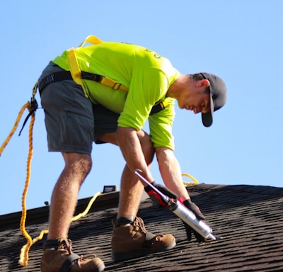 a man in a yellow shirt is working on a roof