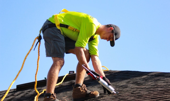 a man in a yellow shirt is working on a roof