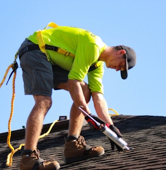 a man in a yellow shirt is working on a roof