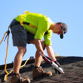 a man in a yellow shirt is working on a roof