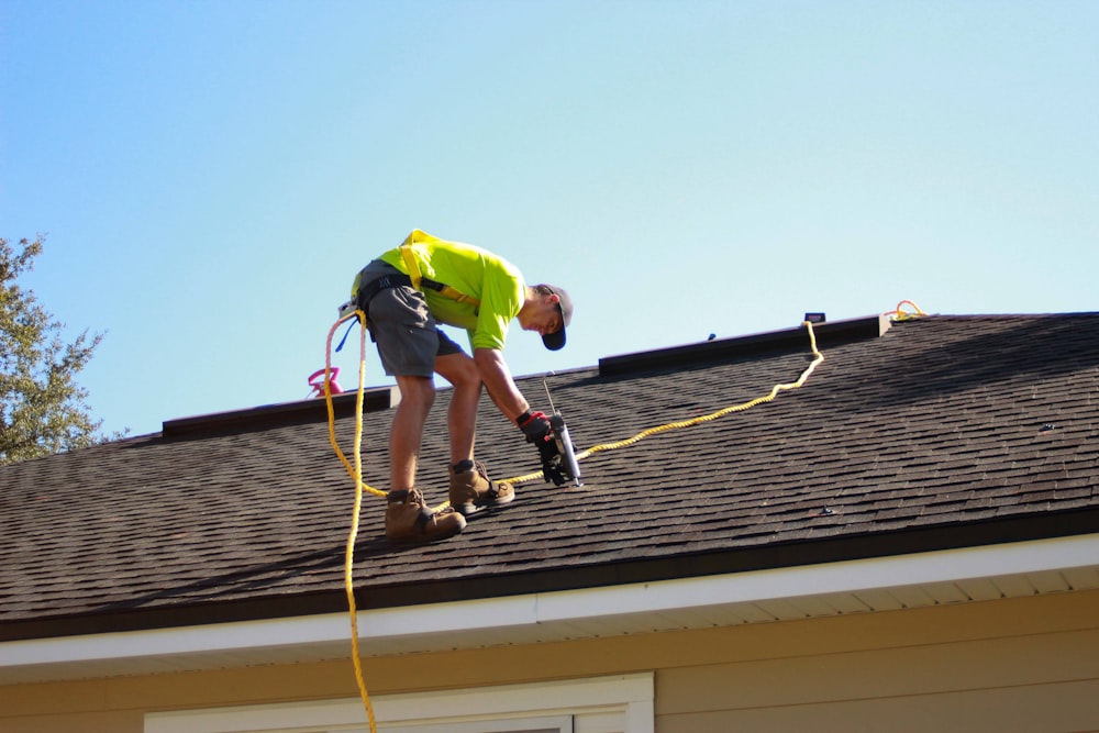um homem trabalhando em um telhado com uma furadeira elétrica