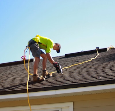 a man working on a roof with a power drill