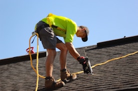 a man working on a roof with a power drill