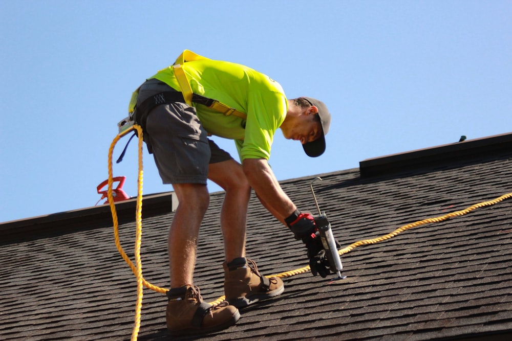 Un hombre trabajando en un techo con un taladro eléctrico