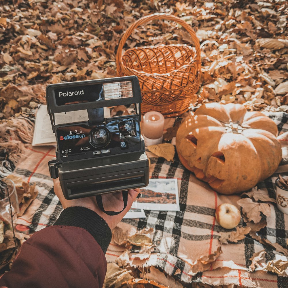 a person holding a camera in front of a pumpkin