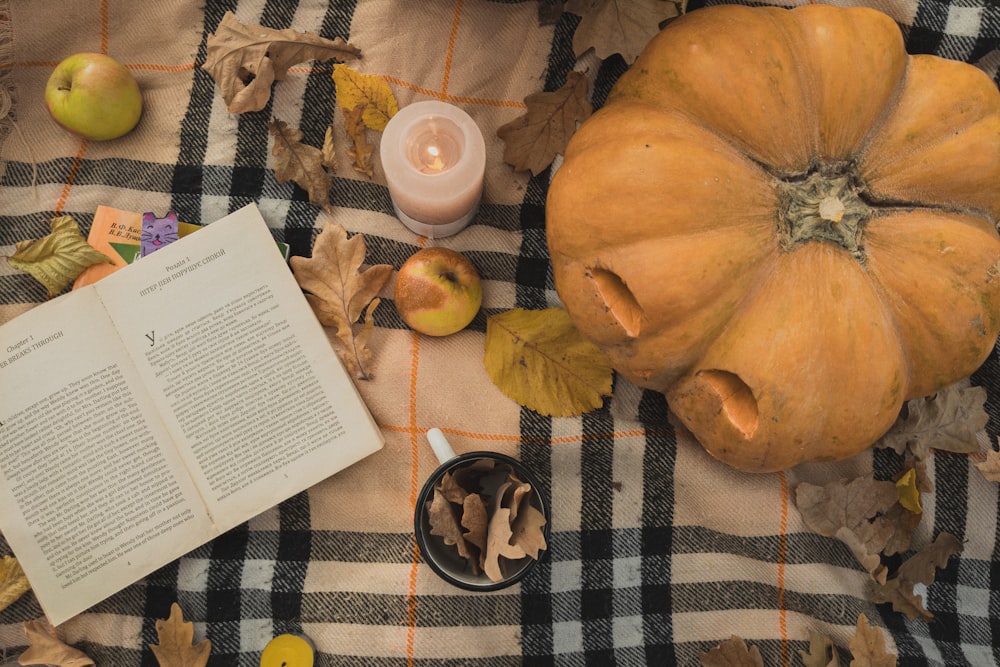 uma mesa coberta com um livro aberto e uma abóbora