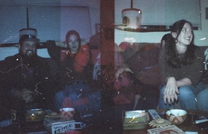 Friends sharing slices around a dimly lit table with dark grey and gold accents.