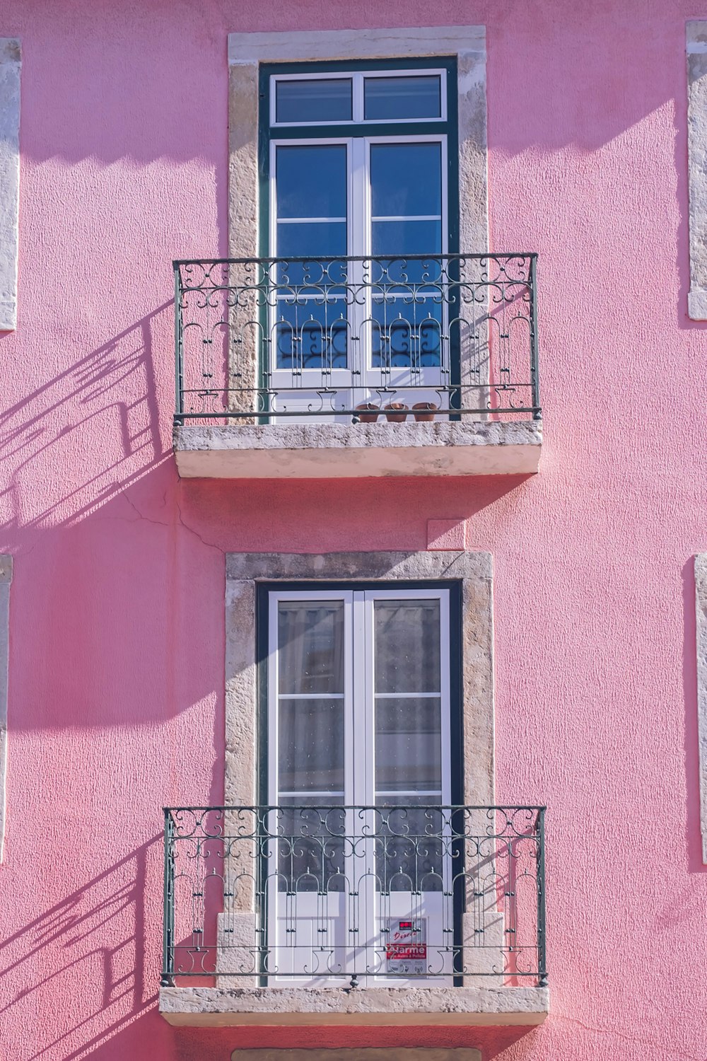 a pink building with two balconies and a balcony