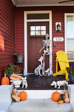 A collection of Halloween decorations including pumpkins, skeletons, and eerie lighting arranged on a porch.
