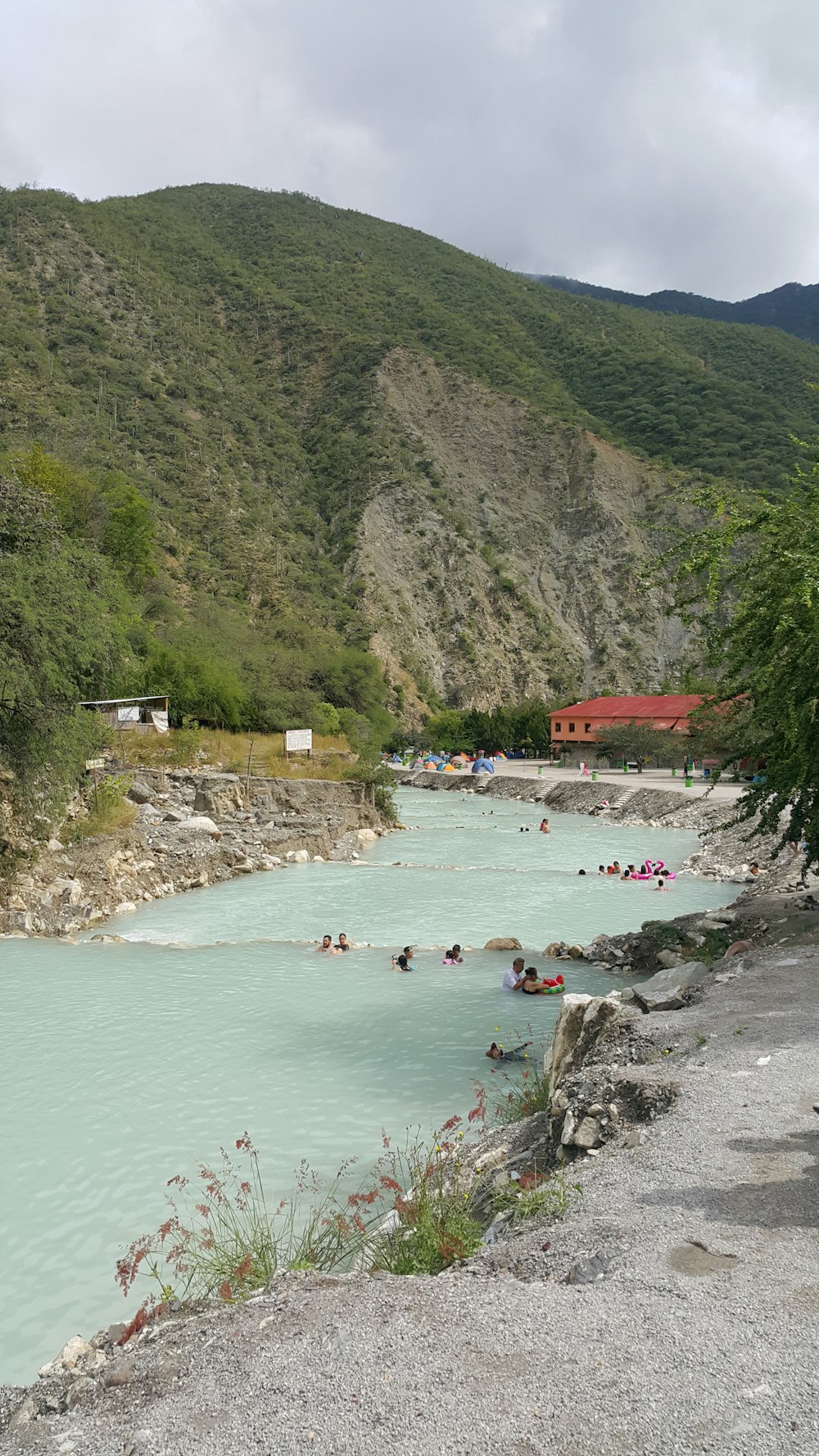 people are swimming in a river near a mountain