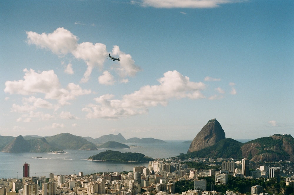 a plane flying over a city with mountains in the background