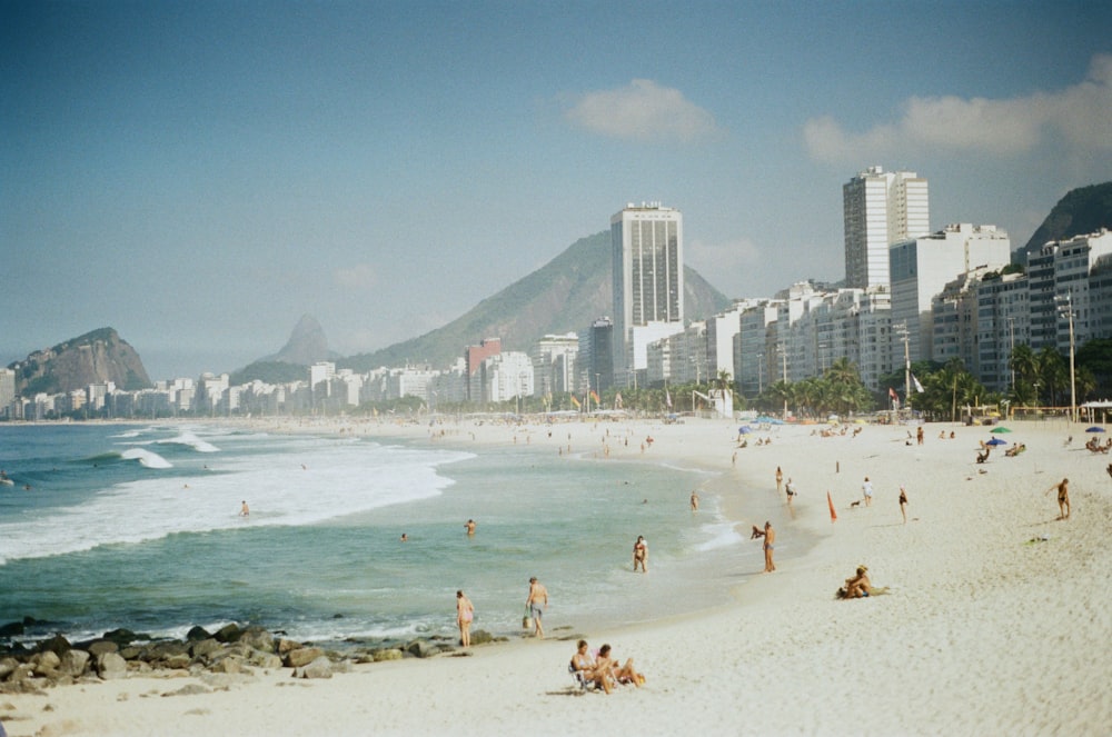 a crowded beach with a city in the background
