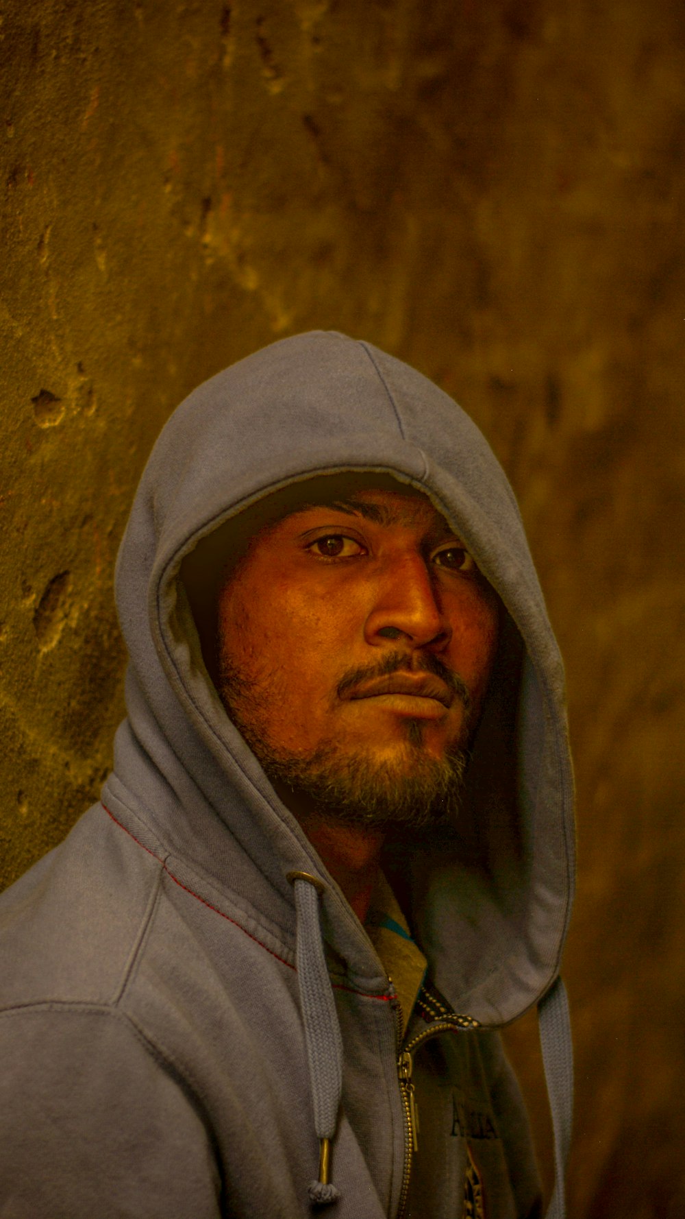 a man in a hoodie standing in front of a wall