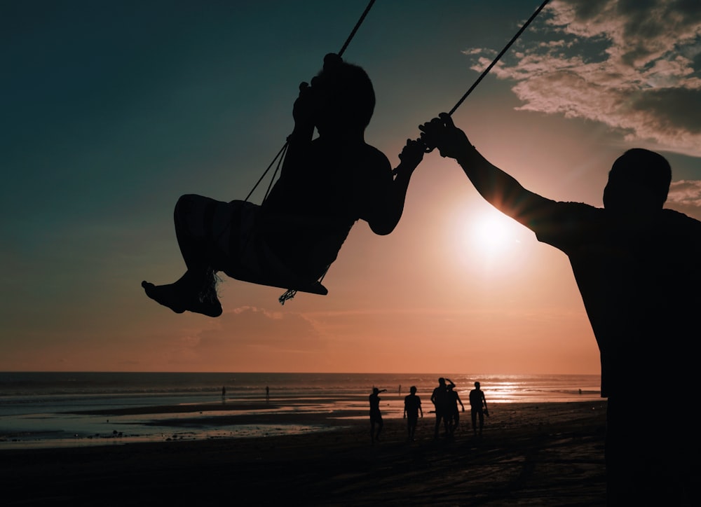 a man is swinging on a swing at the beach