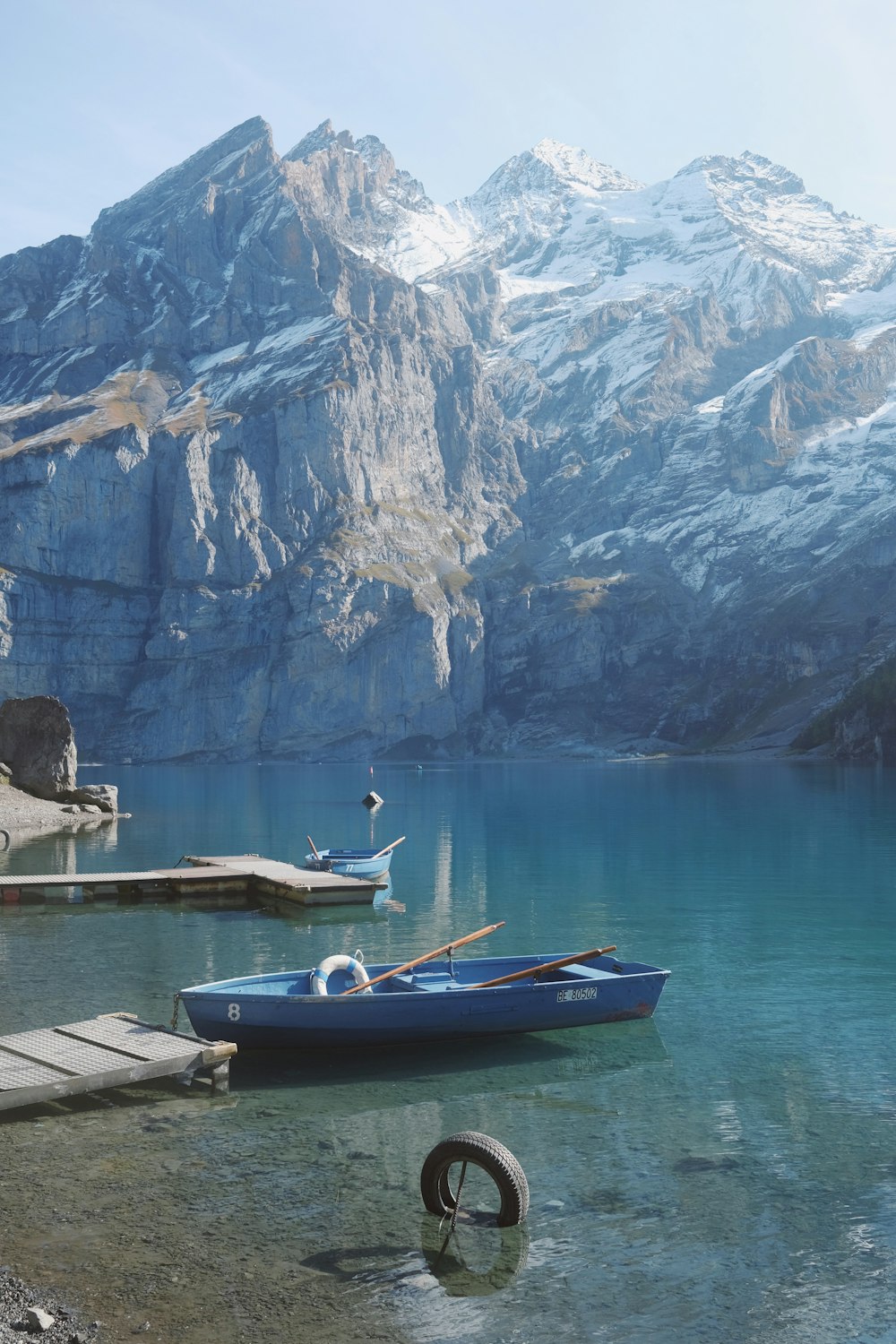 um barco azul sentado no topo de um lago ao lado de uma montanha