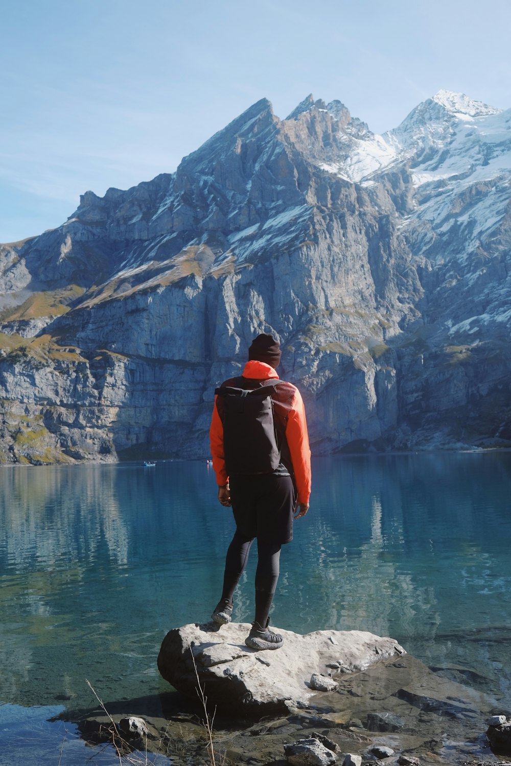 um homem de pé em cima de uma rocha ao lado de um lago