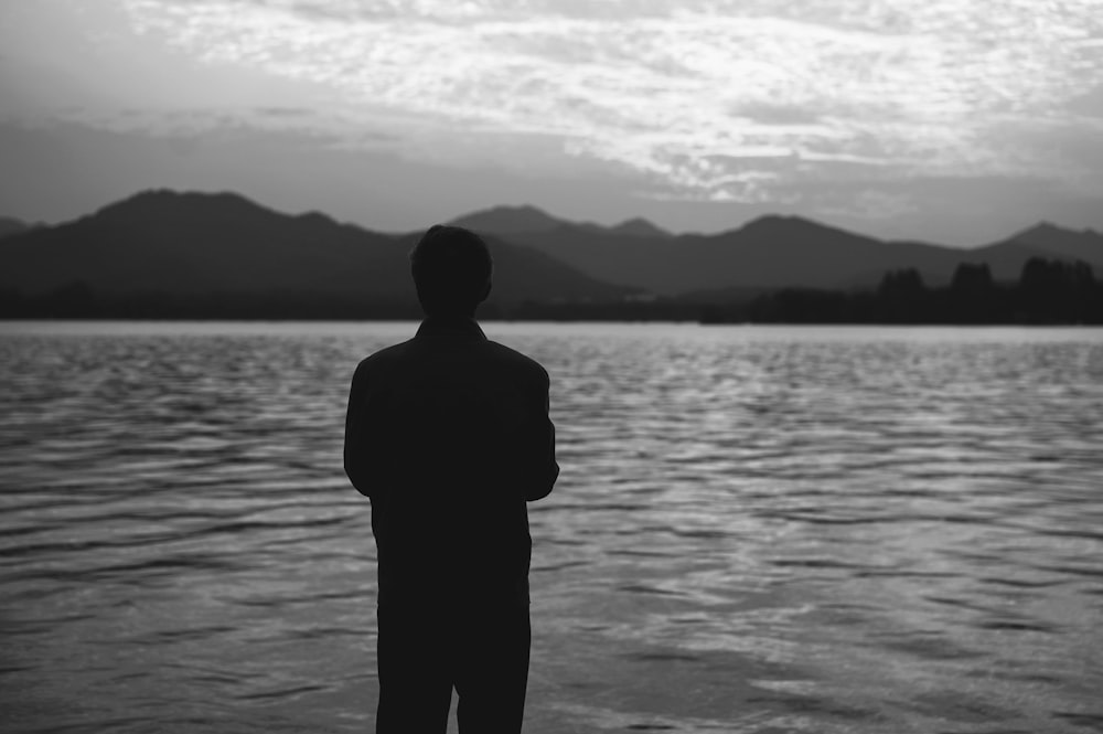 a man standing in front of a body of water