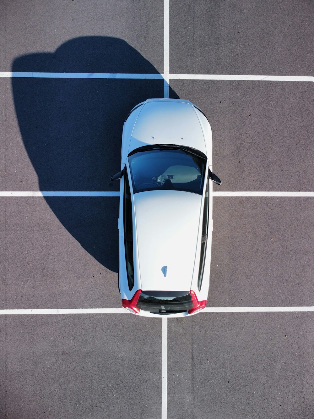 an overhead view of a white car parked in a parking lot