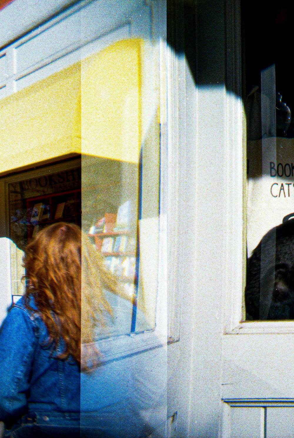 a woman looking out a window at a cat