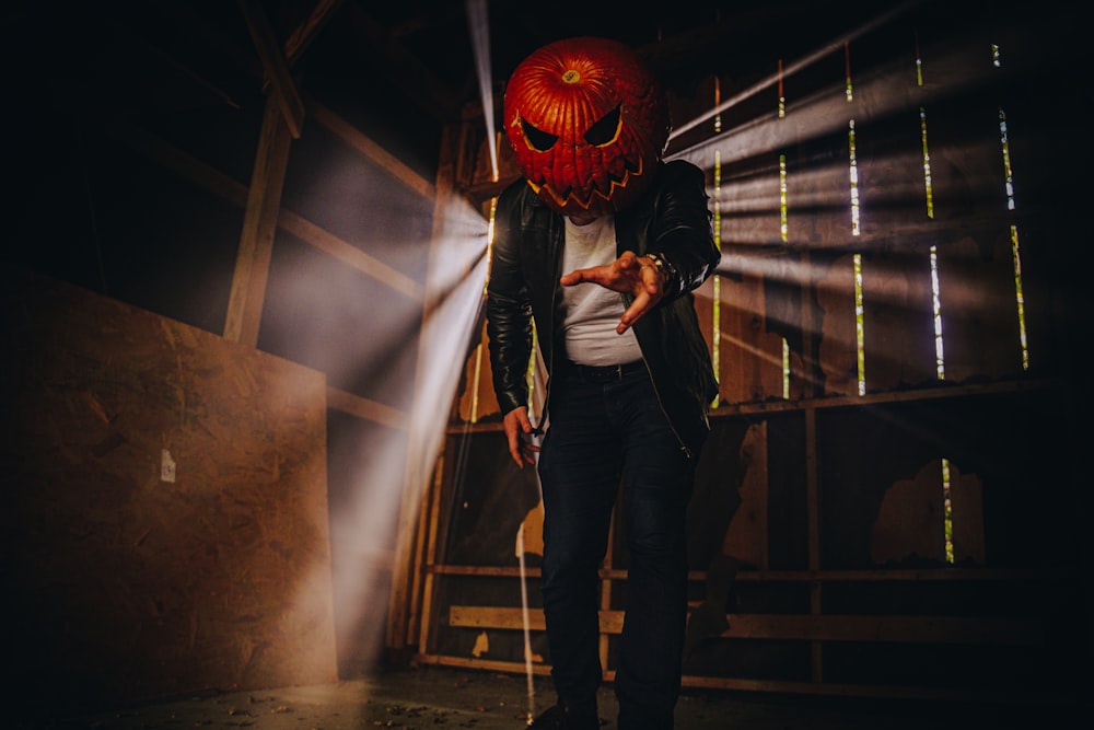 a man wearing a pumpkin mask and holding a cane