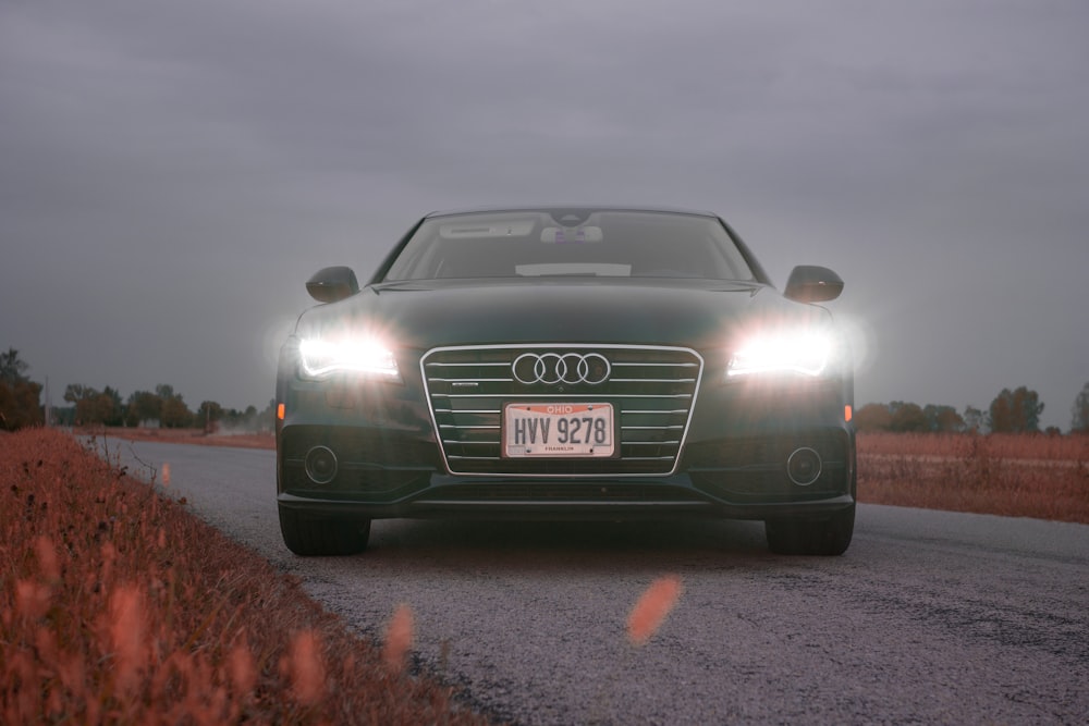 a green car driving down a road next to a field