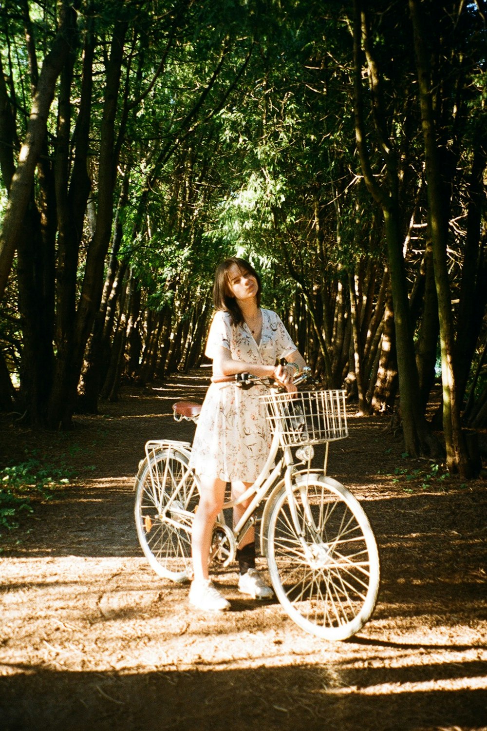 未舗装の道路で自転車の隣に立っている女性