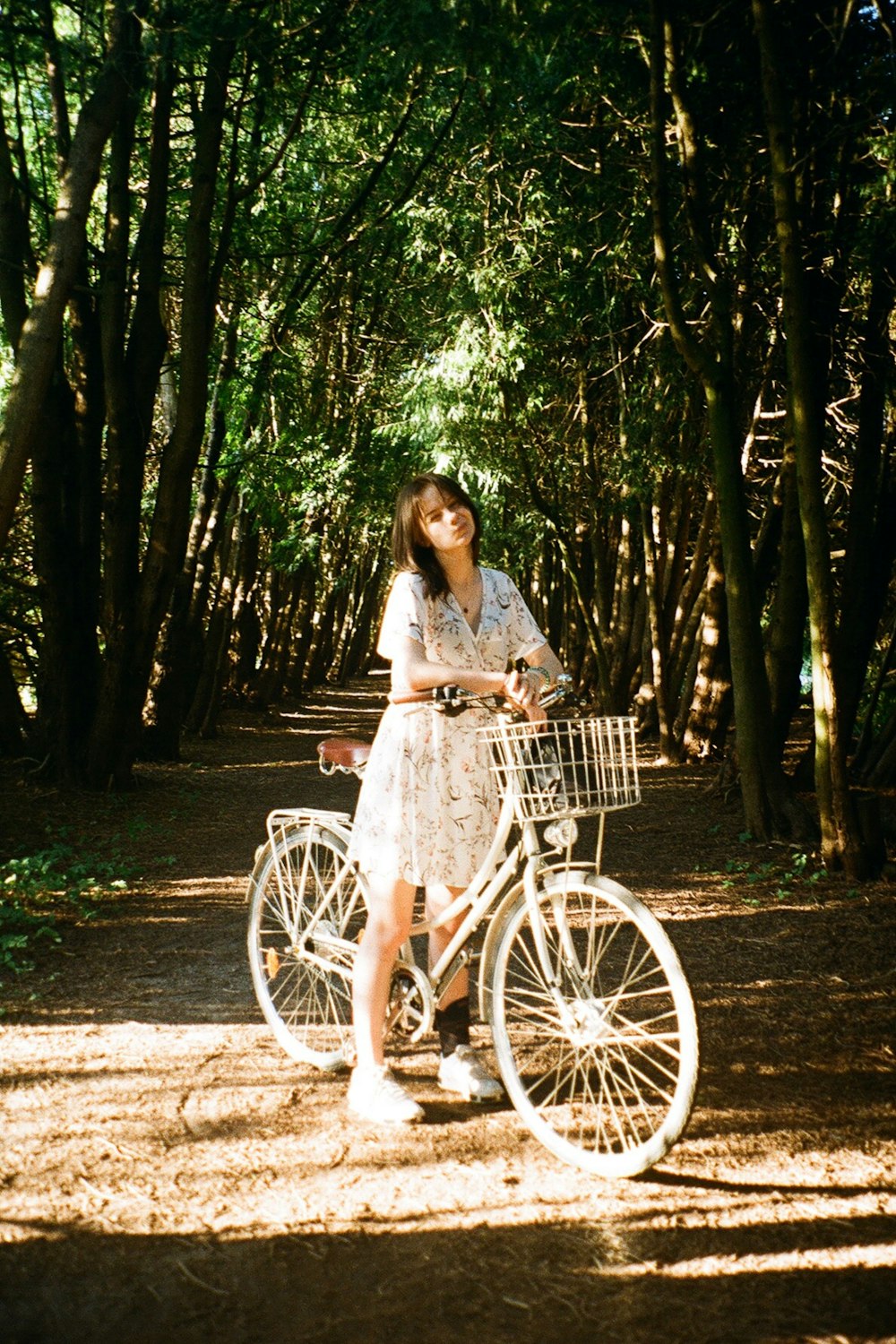 a woman standing next to a bike on a dirt road