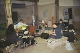 A group of teenagers and adults playing guitars and drums together in a cozy northern Melbourne garage.