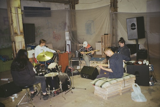A vibrant scene of musicians playing together in a warmly lit rehearsal room with deep blue and golden accents.