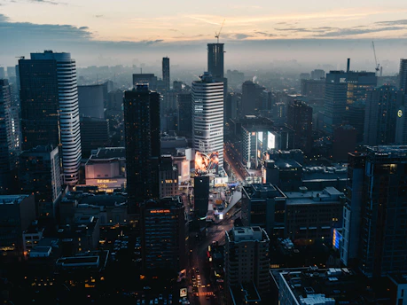 A bustling cityscape in Cambodia showcasing various digital and billboard advertisements at sunset.
