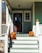 A beautifully decorated porch featuring an array of colorful pumpkins in various sizes, surrounded by autumn leaves and cozy decor.