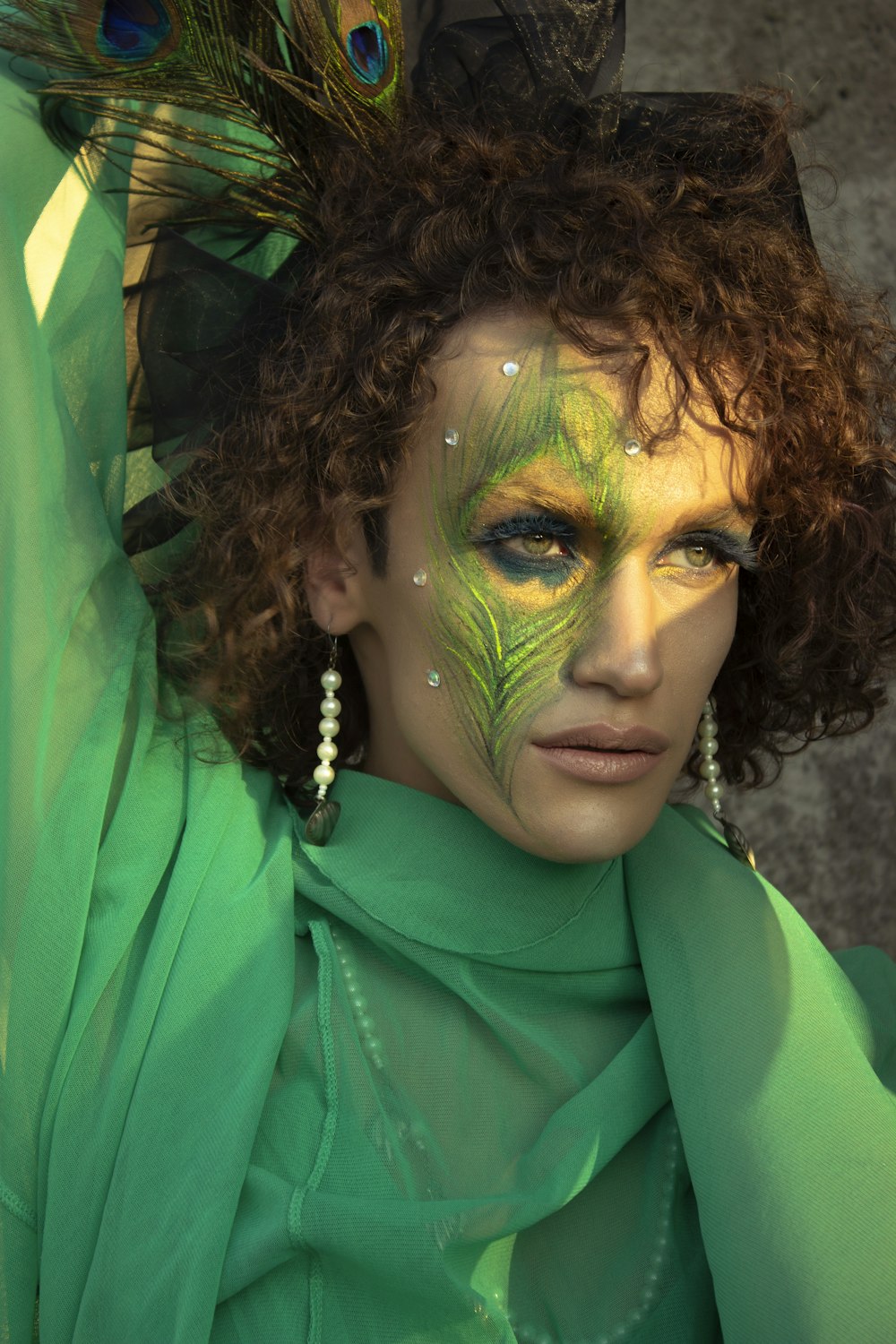 a woman with green makeup and a peacock feather on her head