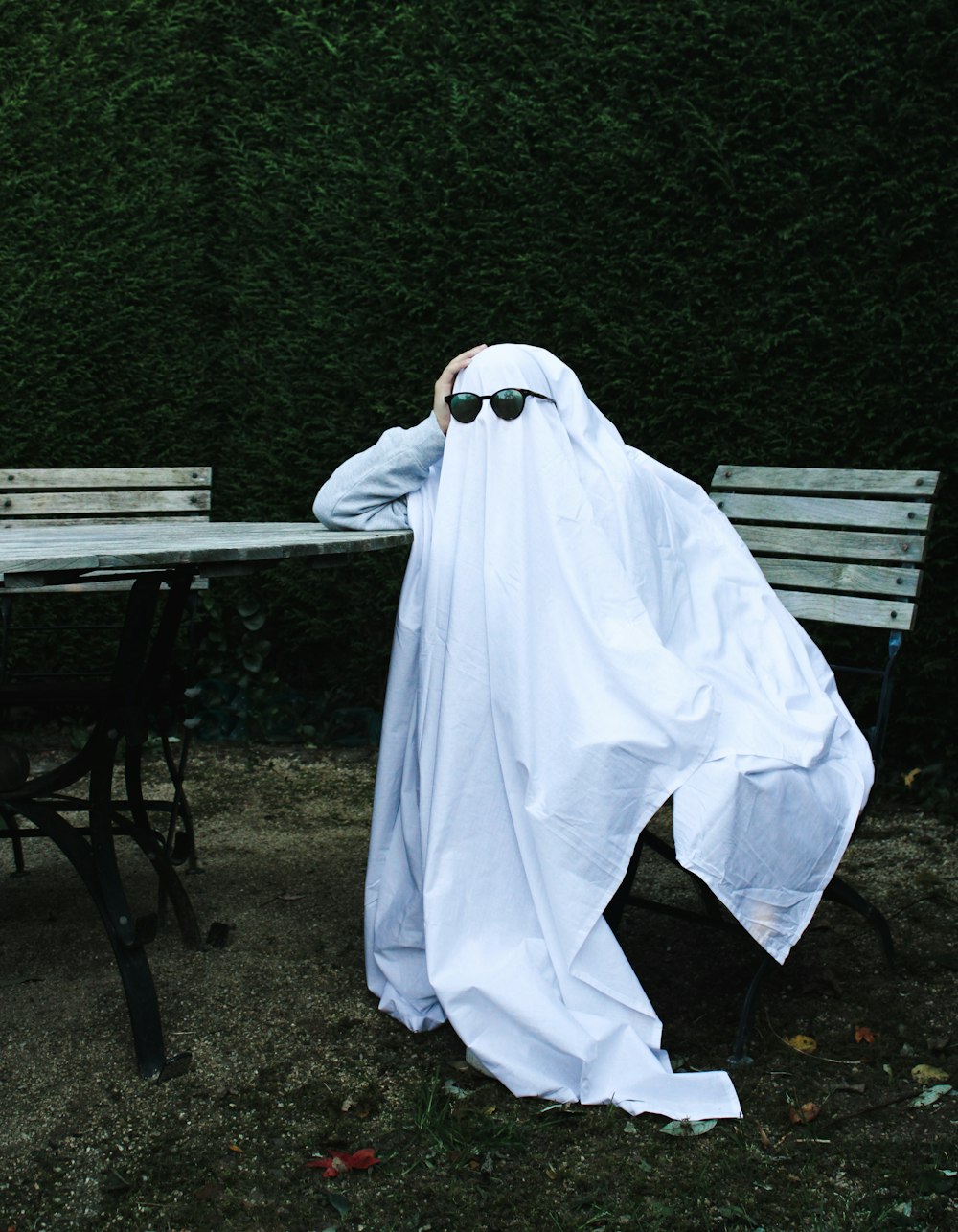 a person in a white robe and sunglasses sitting at a table