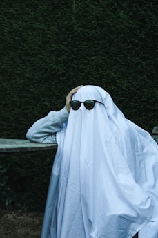 a person with sunglasses covering their face with a blanket