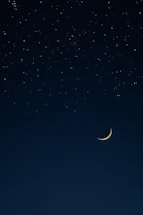 A serene night sky with a golden crescent moon and twinkling stars.