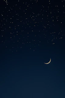 A serene night sky with twinkling stars and a glowing crescent moon.