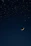 A serene night sky with shimmering stars and a glowing crescent moon.