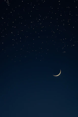 A serene night sky with a glowing golden crescent moon and twinkling stars.