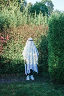 a woman in a white veil standing in front of a hedge