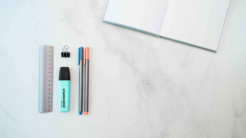 a notebook, pen, ruler, and pencil on a marble surface