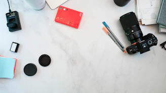 a table with a camera, notebooks, and other items on it